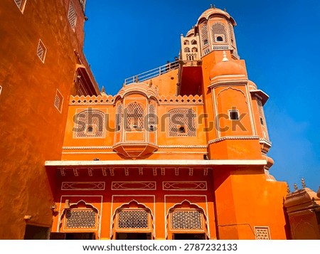 A view from below of the iconic pink and orange facade of the Hawa Mahal (Palace of the Winds) in Jaipur, India
