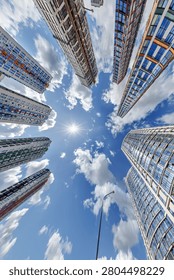 view from below into blue sky with clouds of large modern skyscraper residential complex