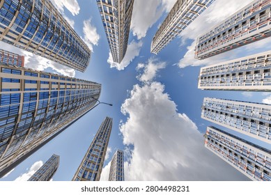 view from below into blue sky with clouds of large modern skyscraper residential complex