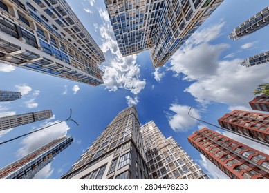 view from below into blue sky with clouds of large modern skyscraper residential complex