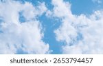 A view from below of large white clouds in the blue sky.