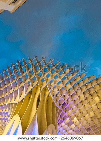 View from below of las setas de sevilla at night with the lights glowing on the wooden structure.