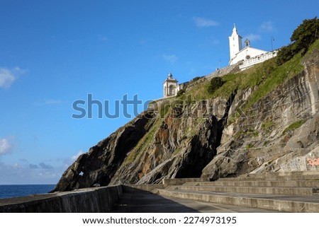 View from below of the lighthouse and the church of the cemetery of Luarca, Spain, located on a cliff facing the sea