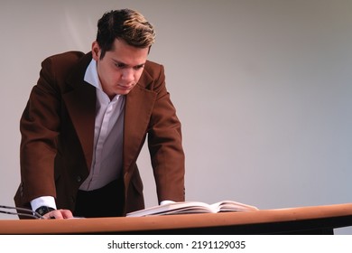 View From Below Of A Man With His Hands On His Desk Thinking About His Work. Business Man Seriously Thinking On A White Background. Caucasian Man In A Suit In His Office.