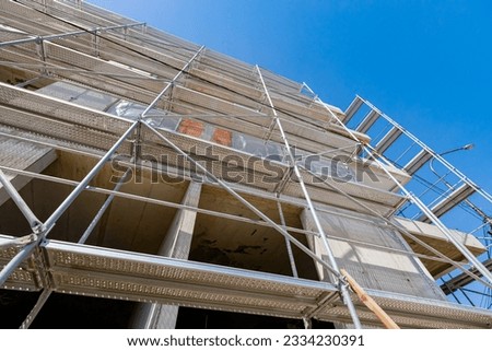 View from below on scaffold placed against unfinished edifice, new residential building under construction.