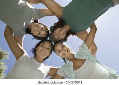 View From Below Portrait Of Four Women In Huddle Against Clear Sky