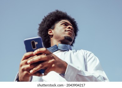 view from below of young african american man using smartphone - Shutterstock ID 2043904217