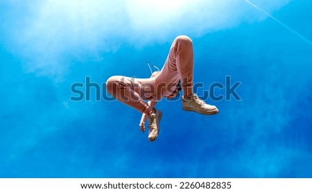view from below to young beautiful woman in pink sports suit jumps full of happiness joy and freedom in a joyful leap into the bright sunny blue sky, copy space