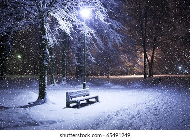 View of bench against christmas tree and shining lantern through snowing. Night shot. - Powered by Shutterstock