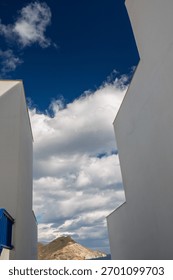 View between two buildings on a blue sky with wild clouds in San José, Almería province, Andalusia, Spain
