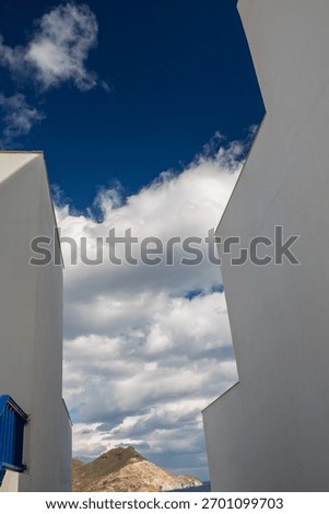 View between two buildings on a blue sky with wild clouds in San José, Almería province, Andalusia, Spain