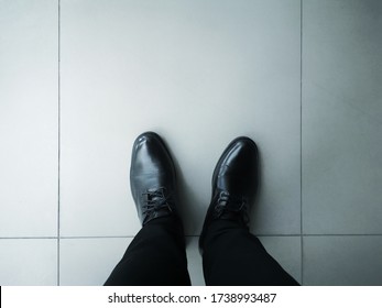  Top view of the black leather shoes on the cement floor. Black men's shoes with long pants on the floor.
