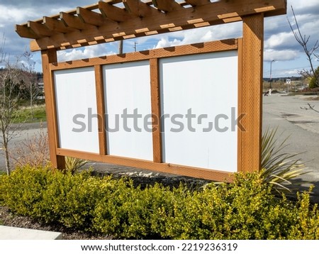 View of a blank outdoor, wooden bulletin board on a bright, sunny day