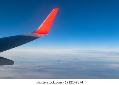 view of the blue clear sky from the height of flight above the clouds from the window of the plane in the bright sun. part of an airplane wing in the frame - Powered by Shutterstock