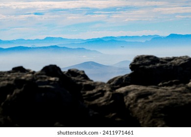 View of the blue mountains, seen from Table Mountain in Cape Town, South Africa. Misty mountains in front of rocks.