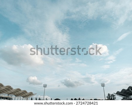 view of blue sky with white clouds above sports stadium.