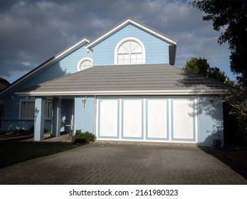View of blue suburban house with garage. Auckland, New Zealand - May 20, 2022