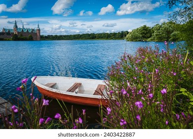 View of boat parked at lake shoreline on nice summer day; wildflowers in foreground 