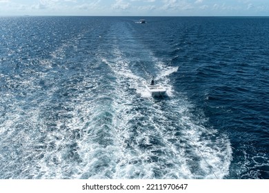 View From The Boat Stern Of The Wake (wash) Effect On The Water From The Motor Placed On The Transom Of A Luxurious Safari Vessel Sailing Between Maldives Islands With A Tied Tiny Dinghy Behind It