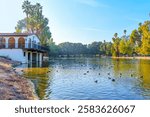 View of Stewart’s Boathouse by Lake Evans featuring ducks and lush vegetation in Fairmount Park, Riverside.