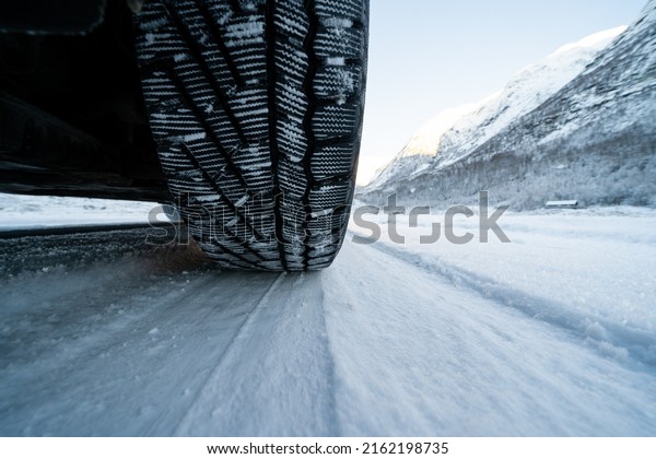 View from the bottom\
of the car on a snowy road where you can see the tread of a winter\
tire in the snow