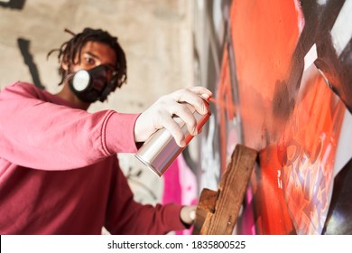 View from the bottom of street artist wearing respirator performing and preparing live murales paint with red aerosol color spray while standing at the stepladder. Stock photo - Powered by Shutterstock