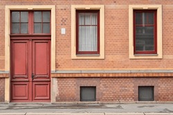 View Of Brick Building With Red Door And Windows