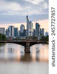 View from a bridge over the River Main to a skyline in the financial district in the background as the sun sets. Twilight in Frankfurt am Main, Hesse Germany