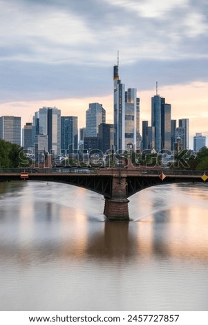 View from a bridge over the River Main to a skyline in the financial district in the background as the sun sets. Twilight in Frankfurt am Main, Hesse Germany