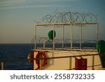 View of the bridge wings of a ship at sea with razor wire on top of the lookout post to keep seagull away from sitting