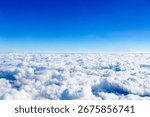 The view of the bright blue cloudy sky from a window on an airplane.