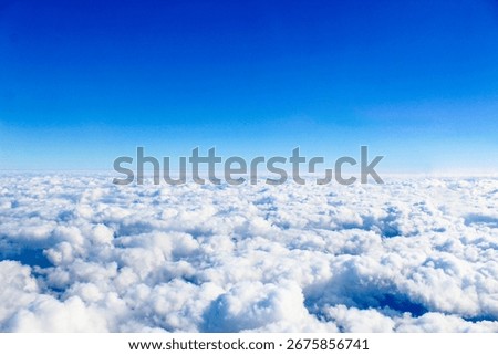 The view of the bright blue cloudy sky from a window on an airplane.
