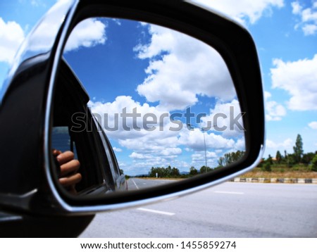 The view of the bright blue sky and clouds from the side mirrors of the cars on the way.
