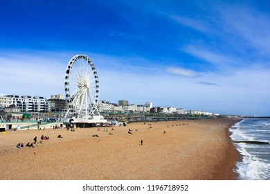 View of Brighton Beach in UK with Ferris wheel and people on beach. 