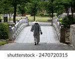 View of the Buddhist monk walking across the stone bridge