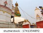 View of buddhist Swayambhunath stupa, also known among tourists as Monkey Temple, with traditional "Eyes of Buddha" painting and Basundhara Devi Temple. Selective focus.