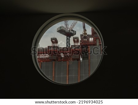 View of Building construction as seen through from round circular window glass on cement wall. Space for text, Selective Focus.