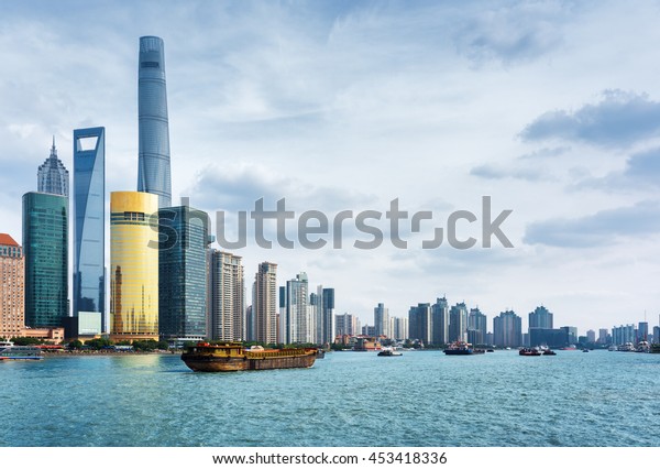 View from the Bund in Shanghai, China. The\
Shanghai Tower, the Shanghai World Financial Center and other\
skyscrapers of downtown are visible at left. Self-propelled barges\
on the Huangpu River.