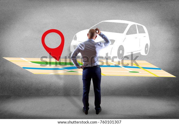 View of a\
Businessman in front of a wall with a Car on a map with a pin\
holder - GPS and localization\
concept