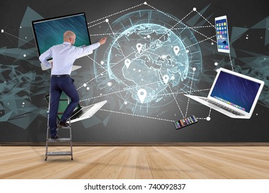 View of a Businessman in front of a wall with Computer and devices displayed on a futuristic interface with interantional network - Multimedia and technology concept