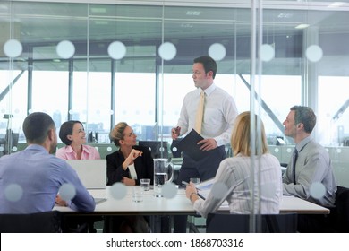 A View Of A Businessman Through The Glass Door While Leading A Meeting In The Conference Room