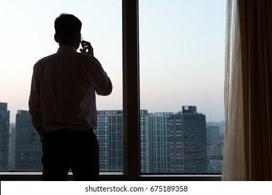 View of businessman's back standing by the glass window having phone call - Shutterstock ID 675189358