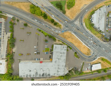 A view of a busy intersection with a large building in the background. The intersection is filled with cars and trucks, and there are several parking lots nearby. Scene is busy and bustling