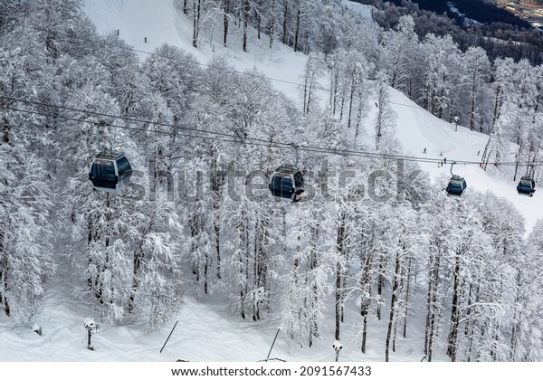 View of the cable car of the gondola lift of the\
Rosa Khutor ski resort in Krasnaya Polyana in winter with the\
snow-capped mountain peaks of the Caucasus in the background - FEB\
04, 2015 SOCHI, RUSSIA