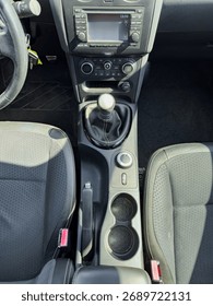The view captures the inside of a car, highlighting the gear shift, center console, and front seats under bright sunlight. The dashboard is partially visible, adding context to the scene.