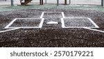 View captures a new artificial baseball field during early spring, showing marked bases and home plate with light snow on top.