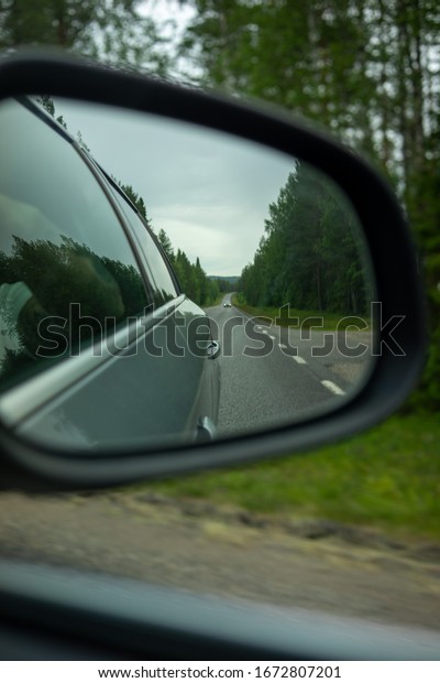 A view of\
a car mirror looking back at the road\
