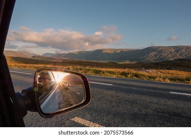 View From A Car On A Mountains And Reflection In A Car Mirror Of A Sun Rise Over Mountain Peak. Connemara, County Galway, Ireland. Car Travel With Stunning Nature Scenery. Teal And Orange Colors.