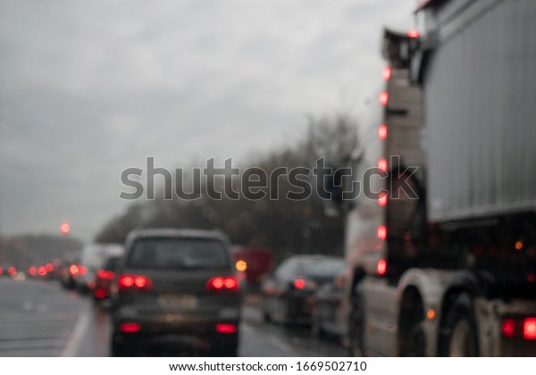 View from a car on a traffic jam on a rainy\
gloomy day, Raindrops on the glass in focus, commuters cars out of\
focus. Concept heavy urban\
traffic.