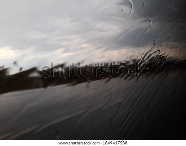View of a car side mirror from inside\
the car with condensation and rain on the glass\
window